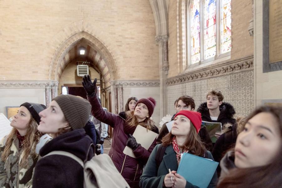 Group of people in winter clothing look up in an old building