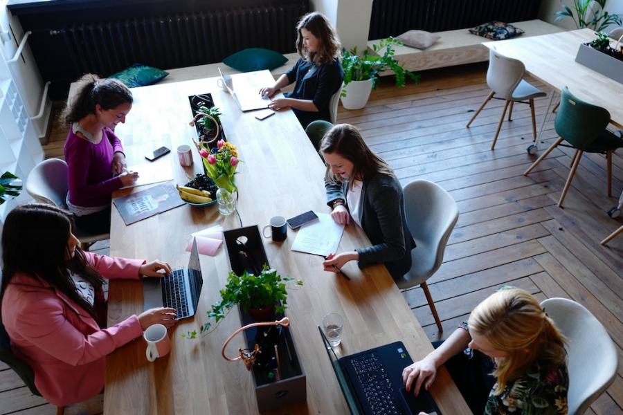Five people working on laptops at a long table