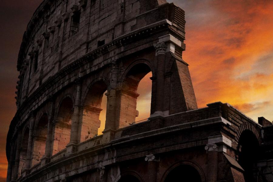 Stone ruins of Roman Colosseum backed by red sunset