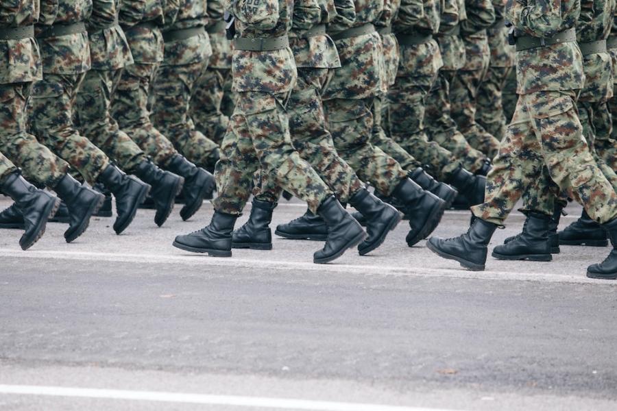 Soldiers dressed in army camouflage march in formation 