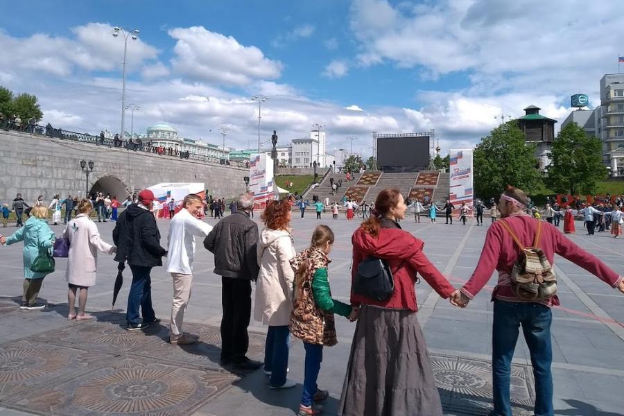 People in a town square hold hands in a large circle
