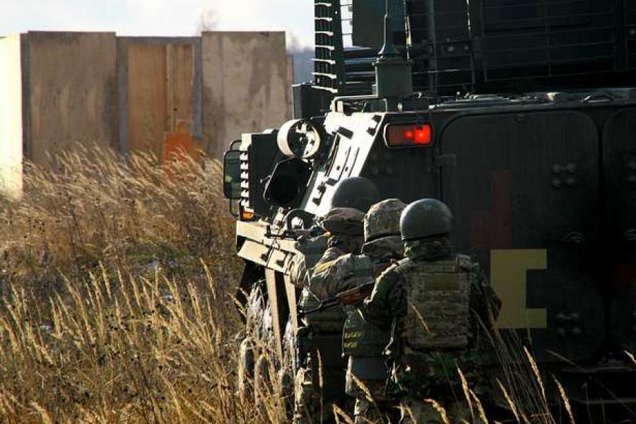 Three solders crouch behind a tank