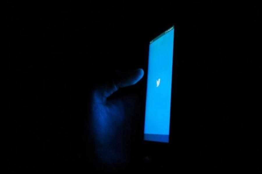 Blue phone screen glows against a dark background