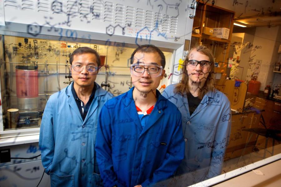 Three people wearing lab coats and protective glasses