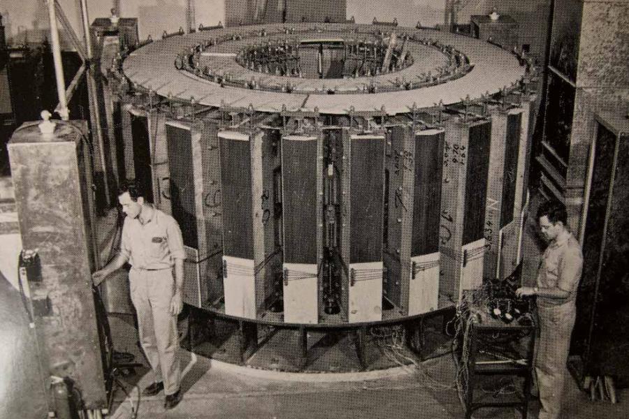 Historical photo of two people working on a large machine