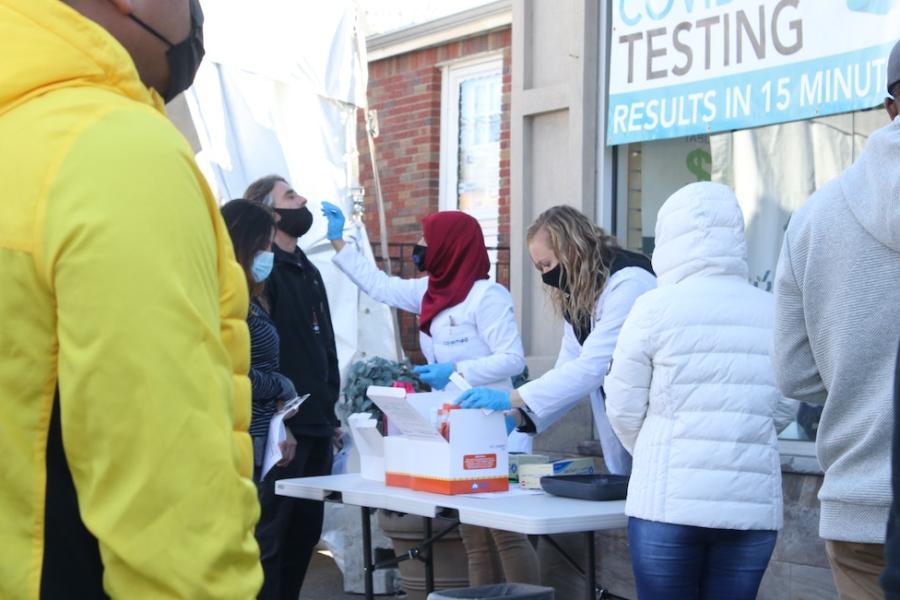 People administer COVID tests at an outdoor table