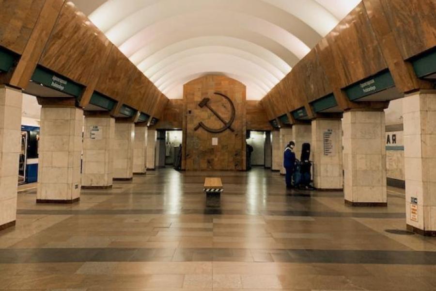 Interior of a building with arched ceiling and smooth floors; Soviet symbol carved into far wall