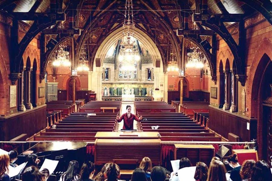 Person leading a singing group in a chapel