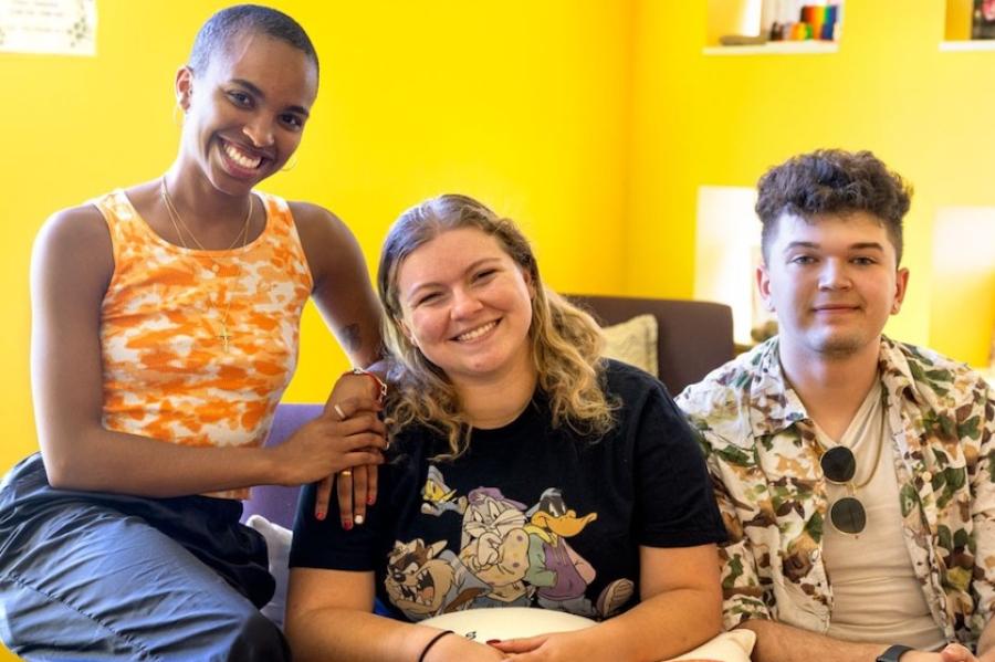 Three people in a sunny room with yellow walls