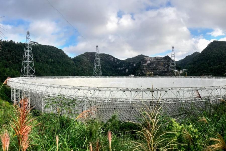 Giant white dish-shaped structure set in lush hills