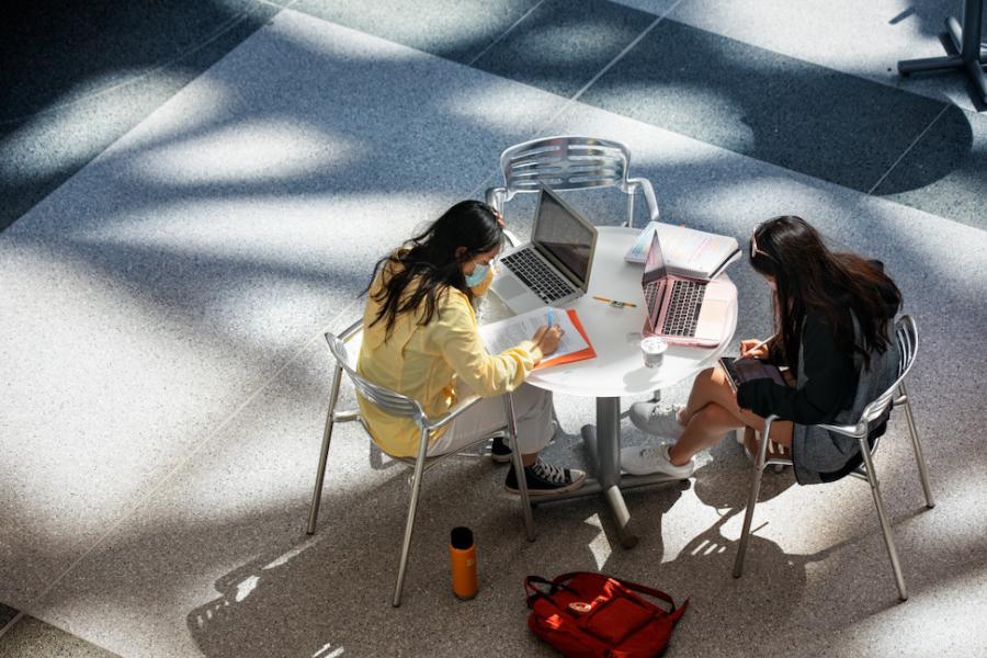 Two people study at a table, seen from above