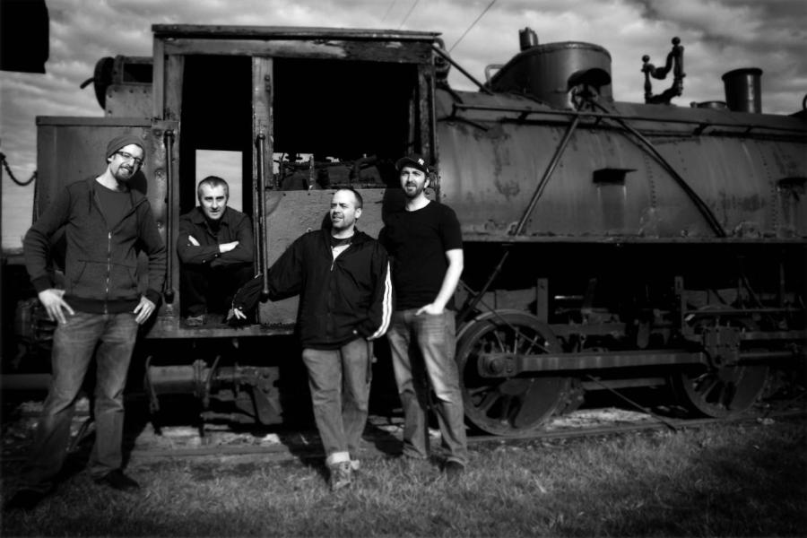 four guys stand by a train