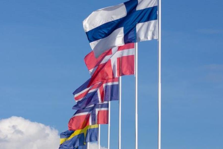 Seven flags on poles against a blue sky