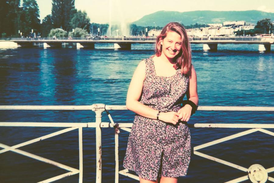 Person standing on a bridge, with a river and city behind