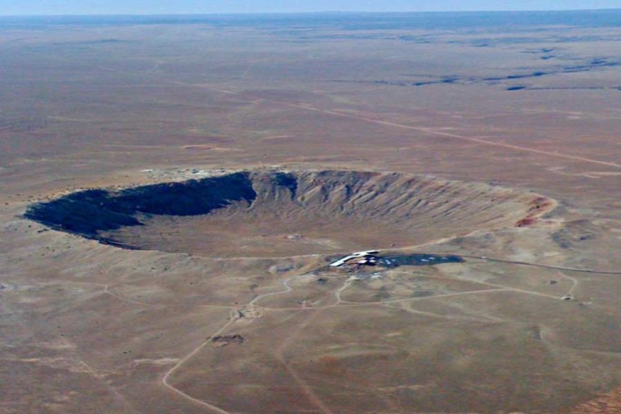 Desert land seen from above, showing a huge crater