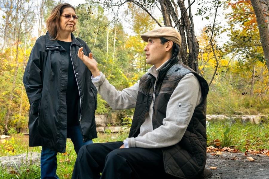 Two people talking in a wooded setting
