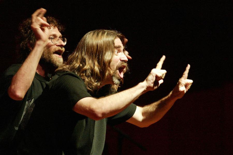 Two people performing with dramatic hand gestures and facial expressions