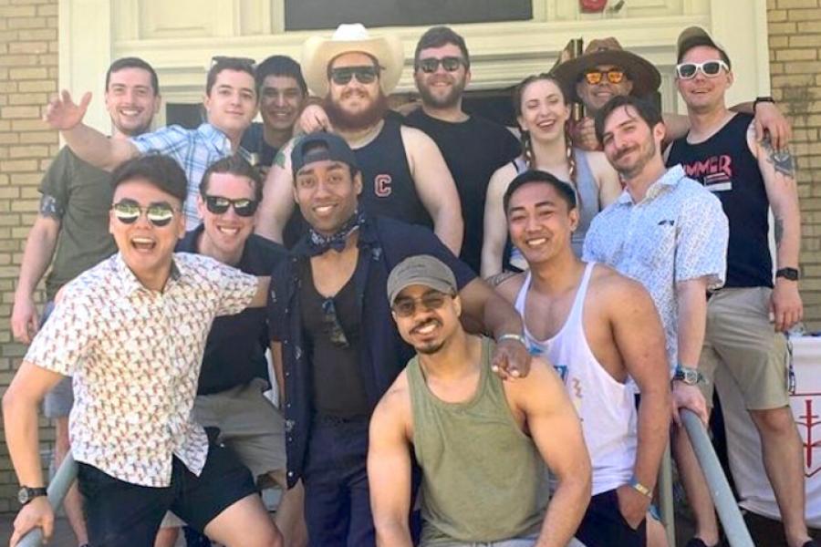 Fourteen people stand on the steps of a house, ready to party