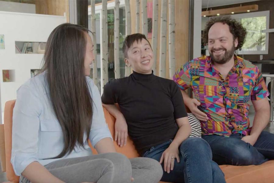 Three people sitting on a couch, laughing