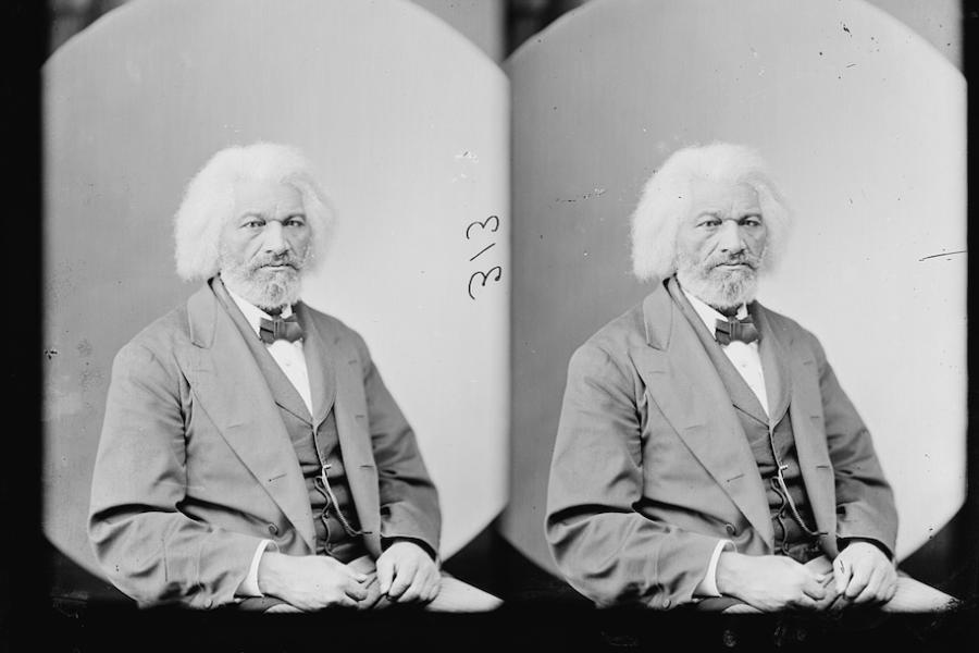 Historical black and white photo of a person seated, in formal clothes and a serious expression