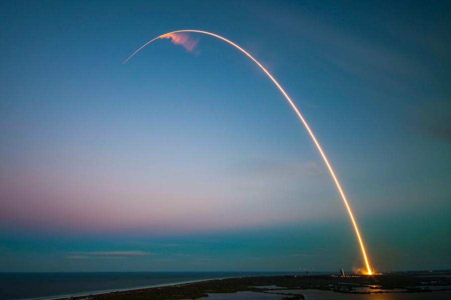 Yellow streak against a pale blue and pink sky; a missile launch