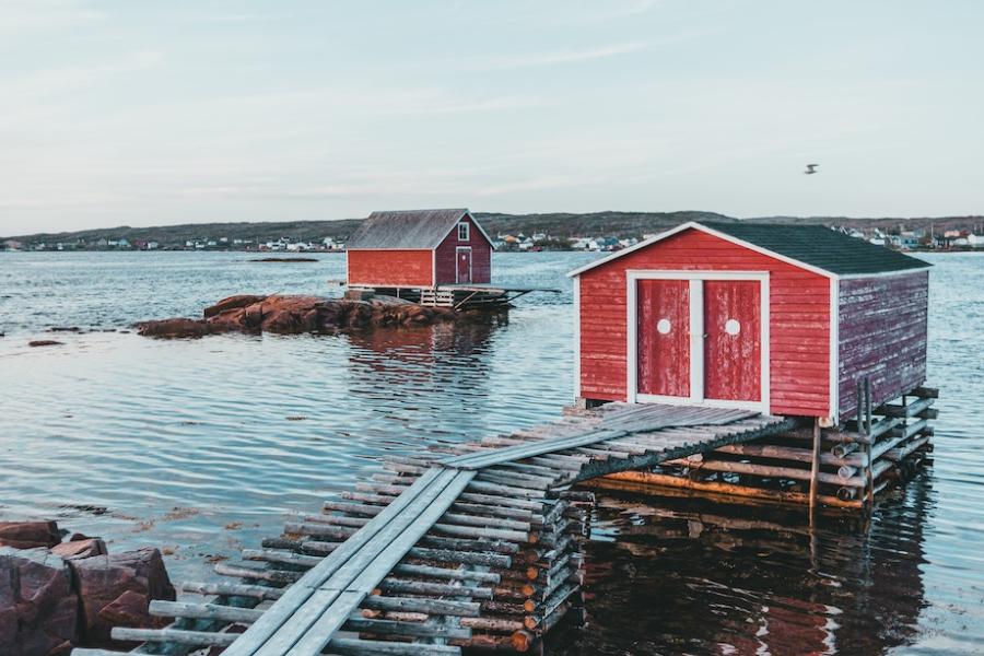 Two red shacks on log platforms in a bay