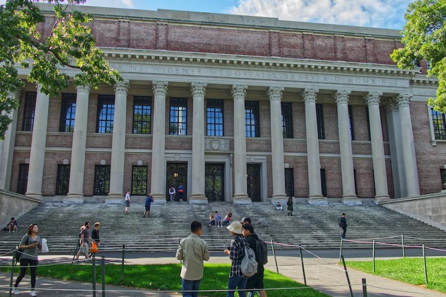 Brick building with stone columns; people walking on a lawn
