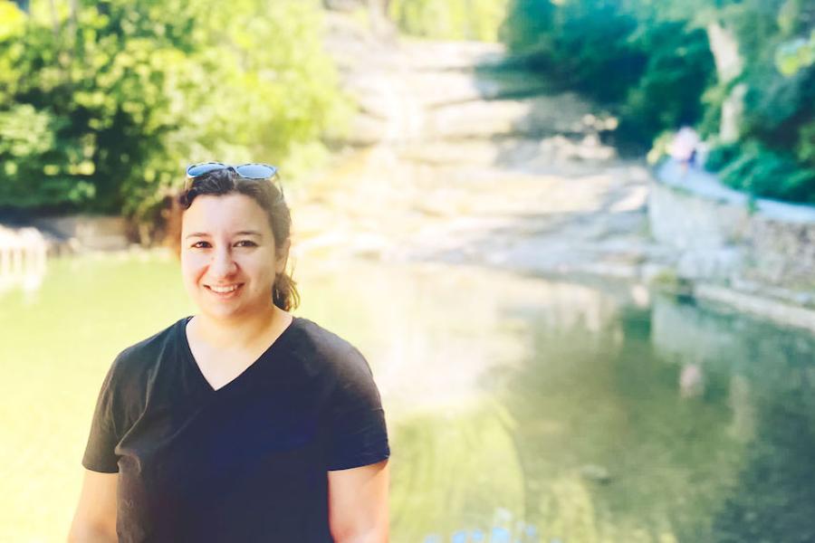 Person in front of a pool of water surrounded by stone banks