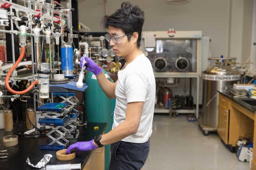 Person working in a lab, wearing safety goggles and purple gloves
