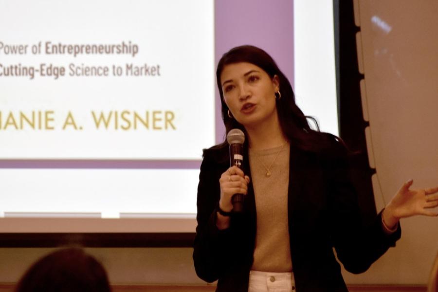 Person speaks with a microphone in front of a screen