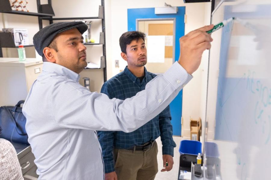 Two people looking at a white board