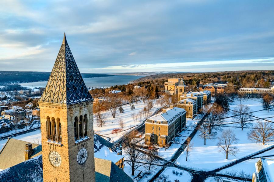 Clock tower in foreground, snowy college campus in the distance, seen from above in low light