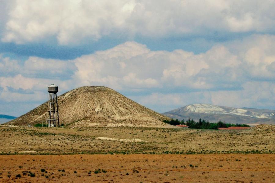 Dry landscape featuring a hill and partly cloudy sky