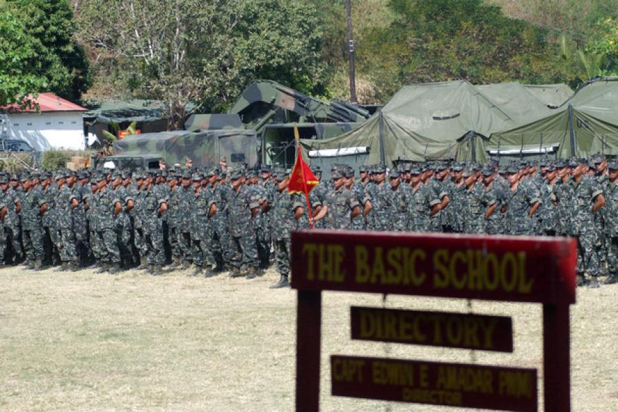 Soldiers stand in formation beyond a wooden sign