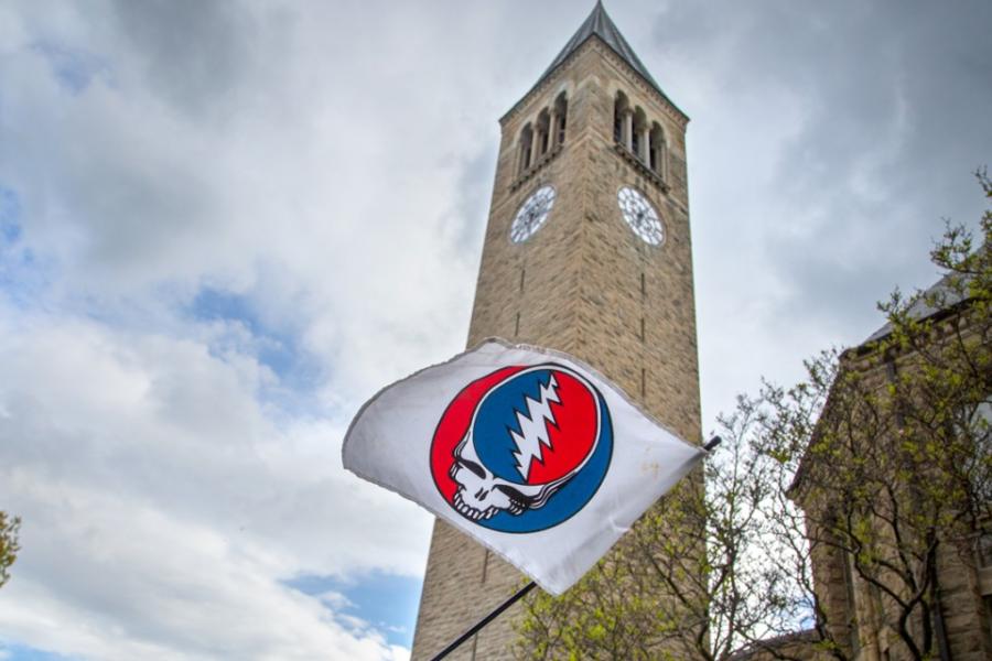 White flag showing a red, white and blue skull graphic in front of a campus clock tower
