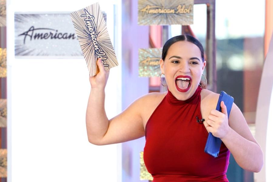 Person shouts joyfully, waving a card that says "American Idol"