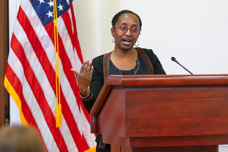 Person speaking at a podium; American flag in the background