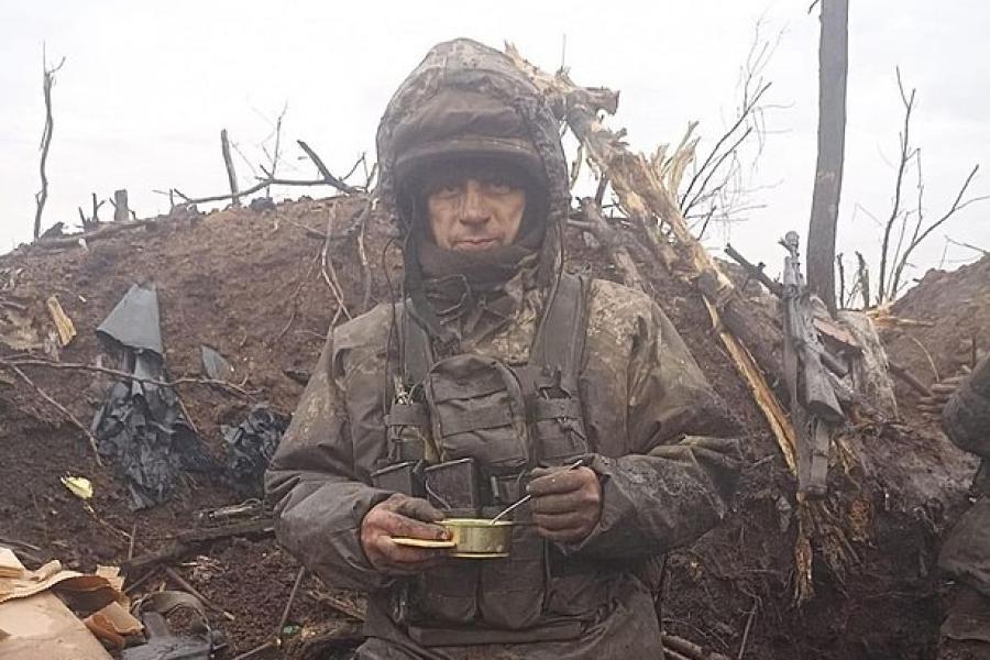 Solder wearing battle-worn clothing, eating out of a cup