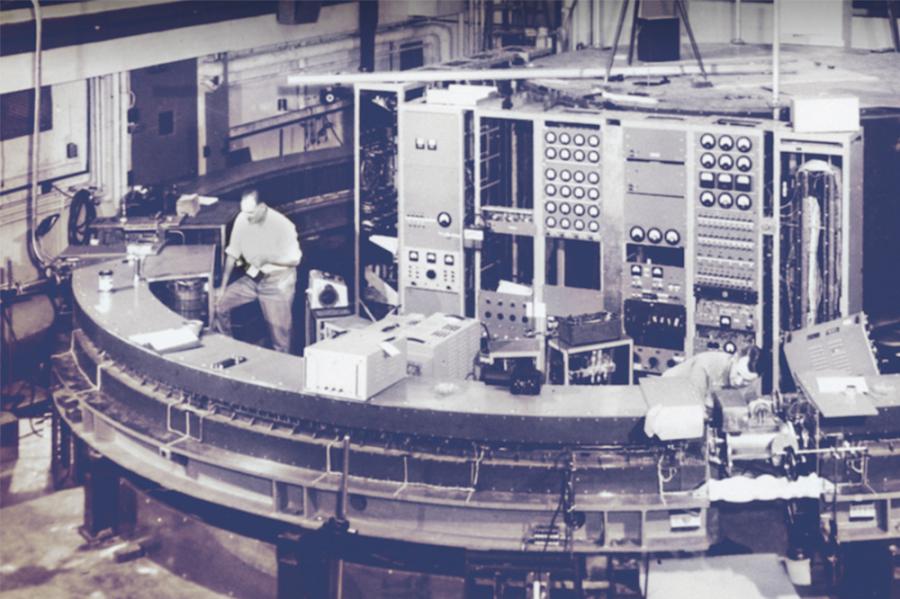 Black and white photo of a person standing in front of large equipment