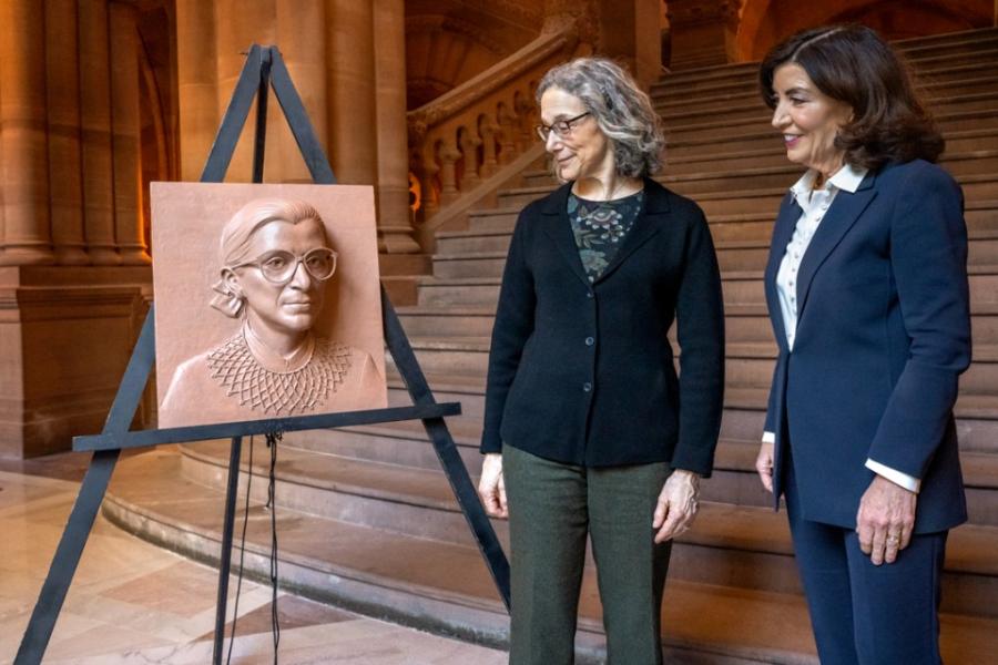 Two people look at a piece of art portraying the face of Ruth Bader Ginsburg