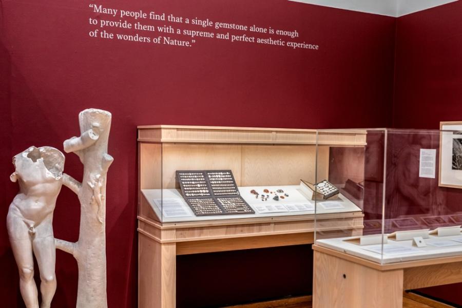 Museum display of a nude sculpture, cases of objects and a quote on the wall