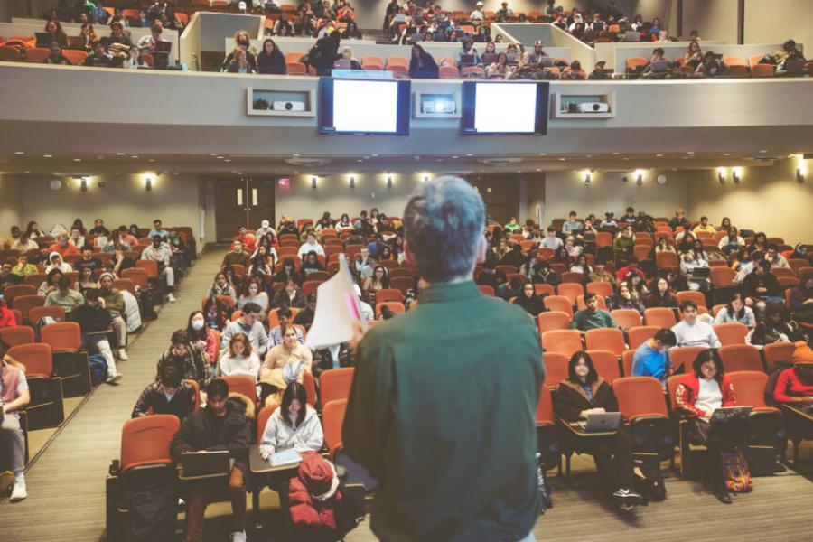 Person stands in front of a mostly full auditorium
