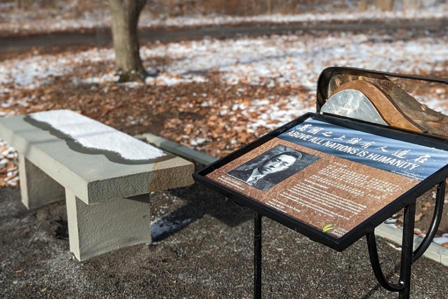 In a natural areas, a stone bench is next to an interpretive sign