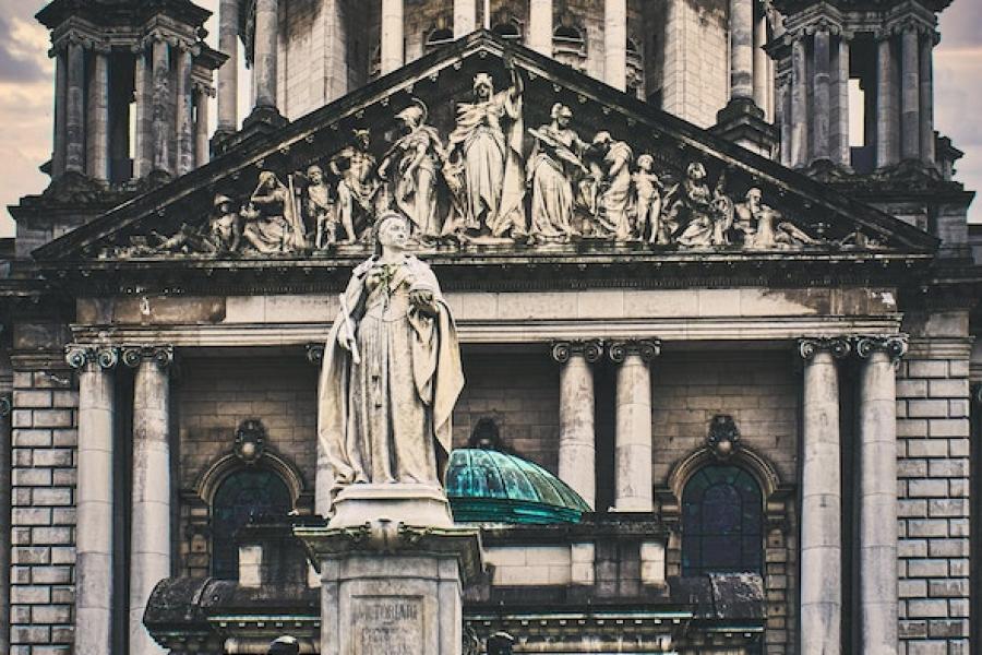 Stone building with a green dome and a sculpture in front