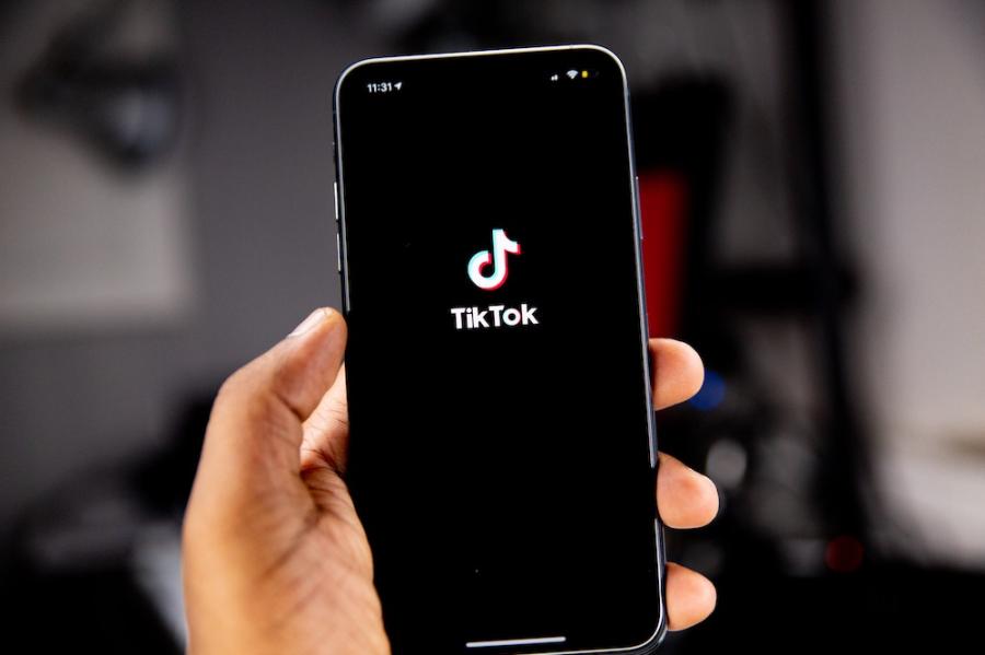 Hand holding a smart phone showing the TikTok icon