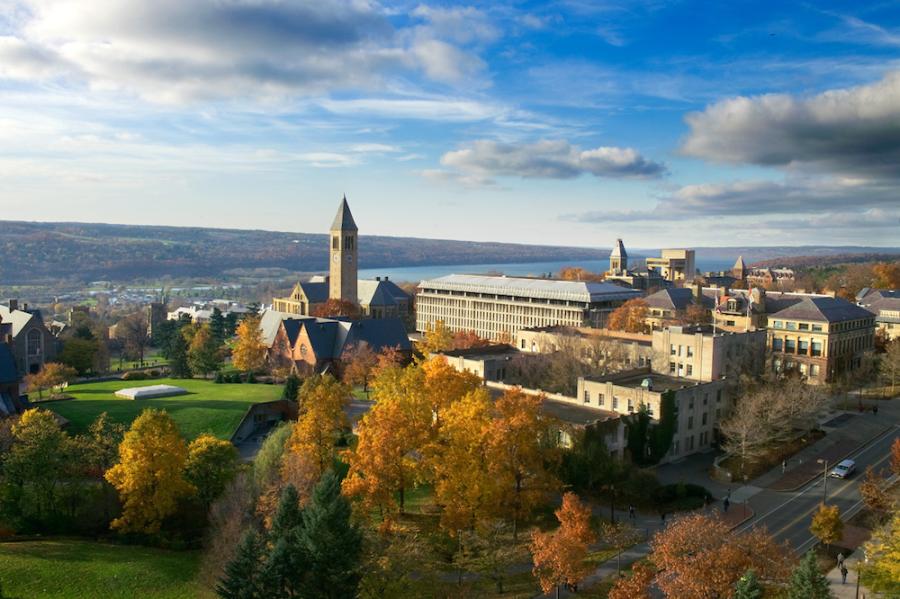 Campus buildings under a blue sky with a lake in the distance