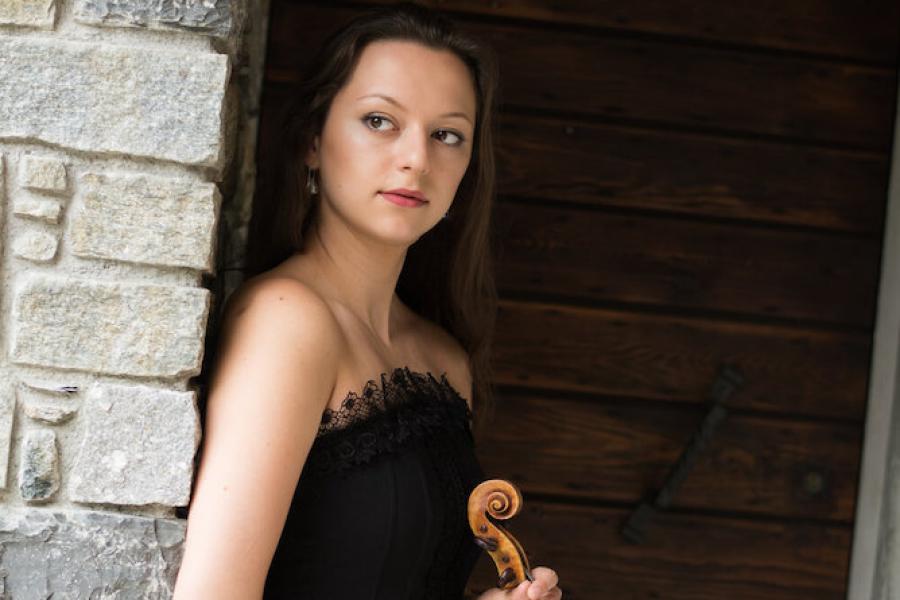Person leaning against a wall, holding a violin