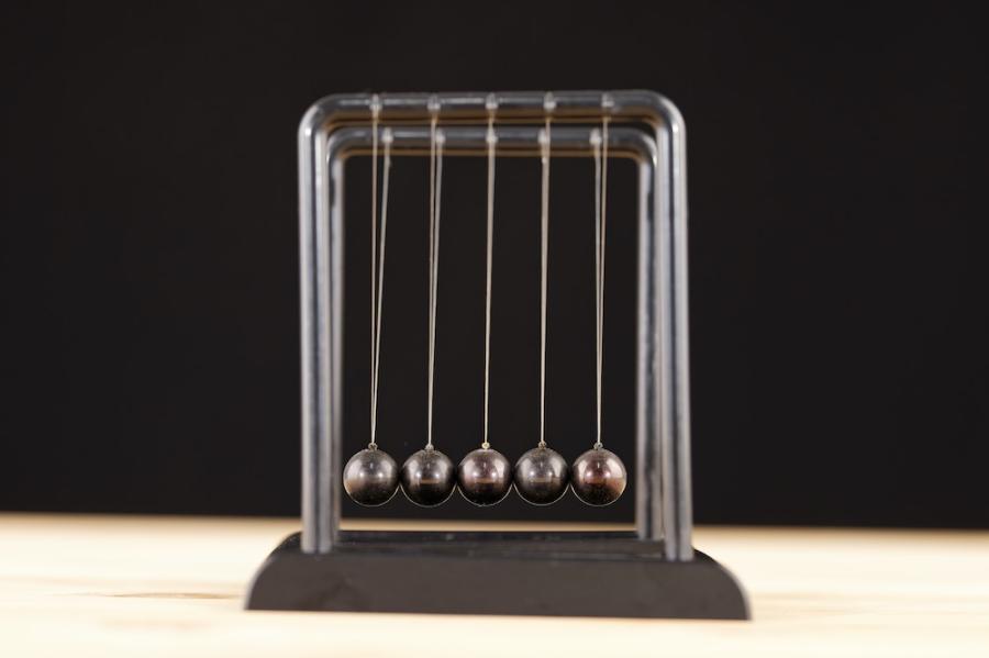 Five metal balls hang from wires in a frame