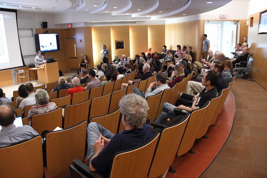 A room full of people facing a speaker at a podum
