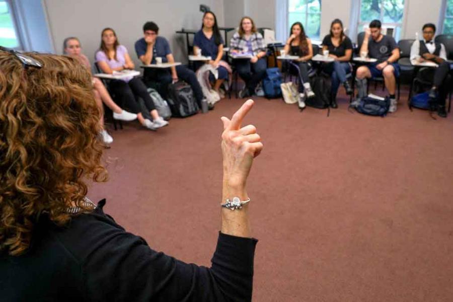 person teaching American Sign Language to a group in a circle